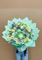 Mint Whisper bouquet featuring green chrysanthemums and white lisianthus wrapped in mint green paper, held against a beige background